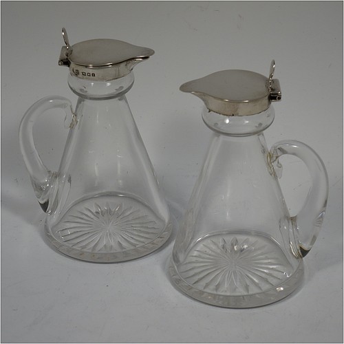 A Sterling Silver pair of whisky toddies or noggins, having round based hand-cut crystal bodies with tapering sides and loop handles, mounted with silver collars and hinged flat lids with thumb-pieces, all sitting on flat star-cut bases. Made by Goldsmiths and Silversmiths of London in 1932. The dimensions of this fine hand-made pair of silver and crystal noggins or toddies are height 11 cms (4.25 inches), and diameter at bases 6.5 cms (2.5 inches).   