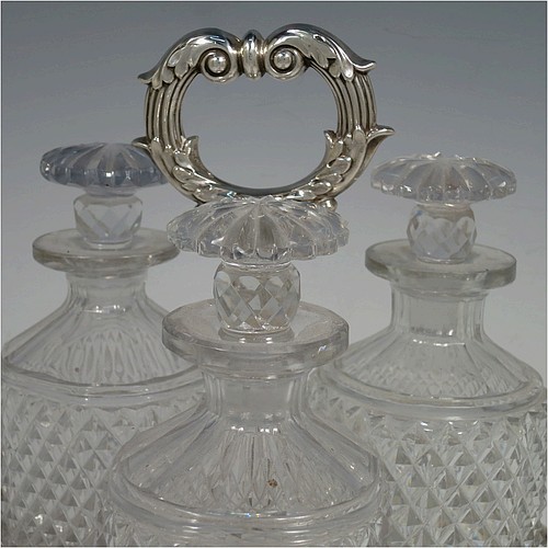 A very handsome Antique Georgian Old Sheffield plated decanter stand, having three hand-cut crystal decanters with original stoppers, sitting inside a carrying frame with a cast anthemion leaf loop handle attached to a hand-chased reeded gallery, which in-turn is attached to a base with shell and gadroon border, and all sitting on three cast scroll feet. Made by Matthew Boulton of Birmingham in ca. 1810. The dimensions of this fine hand-made Old Sheffield plated decanter stand are height 28 cms (11 inches), and width at base 25.5 cms (10 inches).   