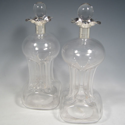 Antique Edwardian pair of sterling silver and cut-crystal glug-glug decanters, having plain bodies with pinched and fluted central waists, plain round necks with four pouring spouts, and original hand-cut stoppers. Made by John Grinsell of Birmingham in 1909. The dimensions of this fine pair of silver and crystal decanters are height 30 cms (11.75 inches), and width 11 cms (4.25 inches).