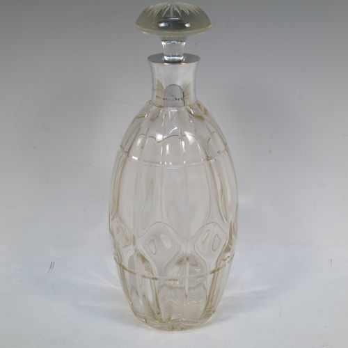 A very unusually designed Sterling Silver and hand-cut crystal decanter, having an oval body , and with hand-cut reeded decoration together with internal lobed work, a plain silver collar, an original hand-cut stopper, and sitting on a flat base with a star-cut. Made by John Grinsell of Birmingham in 1910. The dimensions of this fine hand-made silver and crystal decanter are height 25.5 cms (10 inches), and diameter 10 cms (4 inches).  