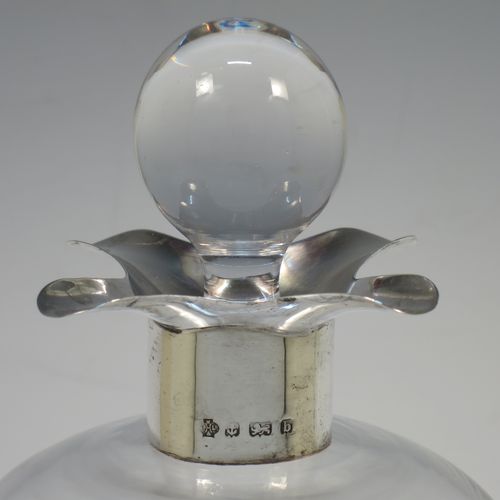 A handsome Antique Victorian Sterling Silver and cut-crystal glug-glug decanter, having a plain and clear body with pinched and fluted central waists, a plain round neck with four pouring spouts, and original hand-cut stopper. Made by William Hutton and Sons of Birmingham in 1901. The dimensions of this fine hand-made antique silver and crystal glug glug decanter are height 27.5 cms (10.75 inches), and width at base 13 cms (5 inches).  