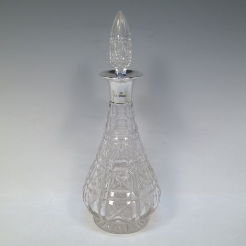 A very handsome Antique Sterling Silver and hand-cut crystal decanter, having a tear-drop shaped body with tapering sides, with hand-cut geometrical decoration, a silver collar and lip, and with original stopper. This elegant silver and crystal decanter was made by R. F. Mosley and Co., of of Sheffield in 1922. The dimensions of this fine hand-made antique silver and crystal decanter are height 32.5 cms (12.75 inches), and diameter at base 11.5 cms (4.5 inches).   