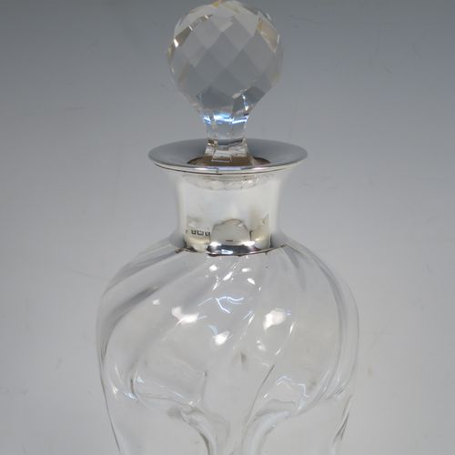 A very pretty Antique Edwardian Sterling Silver and cut-crystal glug-glug decanter, having swirl-flute shoulders and clear bottom body, with four pinched and fluted central waists between, a plain round neck mount, and a hand-cut spherical and faceted crystal stopper. Made in Birmingham in 1909. The dimensions of this fine hand-made antique silver and crystal glug glug decanter are height 28.5 cms (11.25 inches), and width at base 11.5 cms (4.5 inches). 