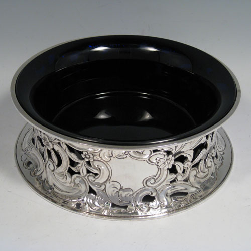 Antique Edwardian sterling silver dish ring, having a hand-chased and pierced body with floral and figural decoration, and with a blue-glass liner bowl. Made by James Parkes of London in 1908. Diameter 20 cms (8 inches), height 7 cms (2.75 inches). Weight approx. 420g (13.5 troy ounces).