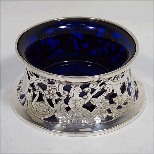 A handsome Antique Victorian Sterling silver miniature dish ring, in an Irish style, having a hand-pierced and chased body with with pastoral scenes, figures, animals, a vacant oval cartouche, and a blue-glass liner. Made by John and Frank Pairpoint of London in 1901. The dimensions of this fine hand-made antique miniature silver dish ring are height 5 cms (2 inches), diameter at base 11 cms (4.3 inches), and it weighs approx. 108g (3.5 troy ounces).    