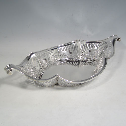 Antique Edwardian sterling silver bread roll table dish, having an oval body with hand-pierced geometrical and floral decoration, with an applied shaped reeded border, with two scroll side handles, and sitting on a flat base. Made by Charles Clement Pilling of London in 1902. The dimensions of this fine hand-made silver bread dish are length 32.5 cms (12.75 inches), width 18 cms (7 inches), height 6.5 cms (2.5 inches), and it weighs approx. 304g (9.8 troy ounces).   