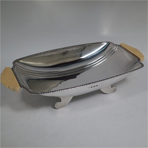 A Sterling Silver Art Deco dish, having a rectangular body with hand-chased reeded decoration, an applied floral border together with two hand-cut stepped bone handles, and sitting on four flanged feet. Made by George Bryan and Co., of Birmingham in 1938. The dimensions of this fine hand-made Art Deco silver serving dish are length 32 cms (12.5 inches), width 16.5 cms (6.5 inches), height 6.5 cms (2.5 inches), and it weighs approx. 620g (20 troy ounces).