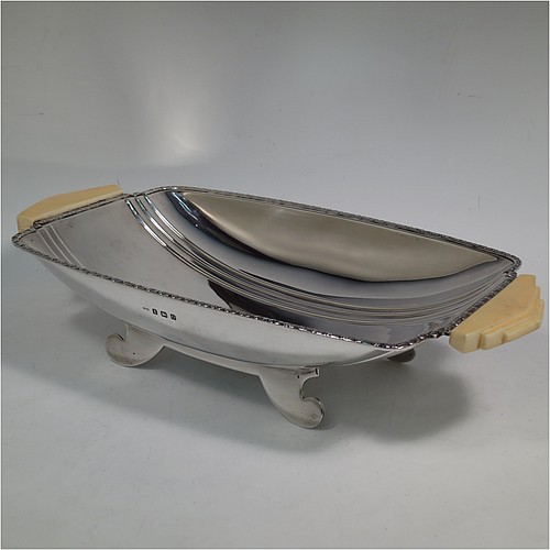 A Sterling Silver Art Deco dish, having a rectangular body with hand-chased reeded decoration, an applied floral border together with two hand-cut stepped bone handles, and sitting on four flanged feet. Made by George Bryan and Co., of Birmingham in 1938. The dimensions of this fine hand-made Art Deco silver serving dish are length 32 cms (12.5 inches), width 16.5 cms (6.5 inches), height 6.5 cms (2.5 inches), and it weighs approx. 620g (20 troy ounces).