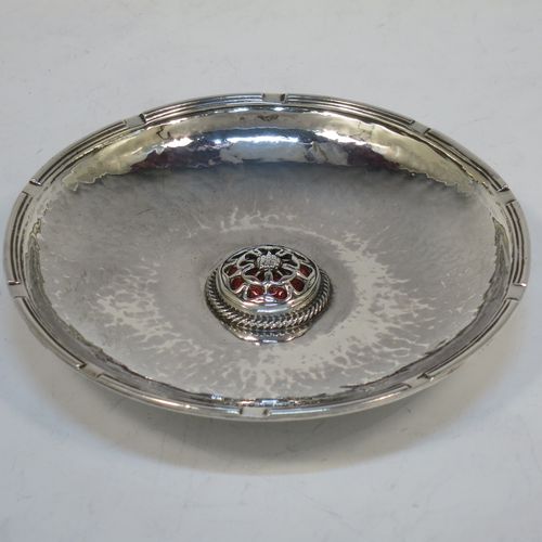 A very beautiful Sterling Silver Arts and Crafts table dish, having a round hand-hammered body, with an applied reed cog border, a central Tudor Rose style boss with an applied rope-twist border and dark red enamel underneath showing through the piercing, and all sitting on a collet foot. Made by Omar Ramsden of London in 1923. The dimensions of this fine hand-made Arts and Crafts silver dish are diameter 11 cms (4.3 inches), and it weighs approx. 93g (3 troy ounces).    