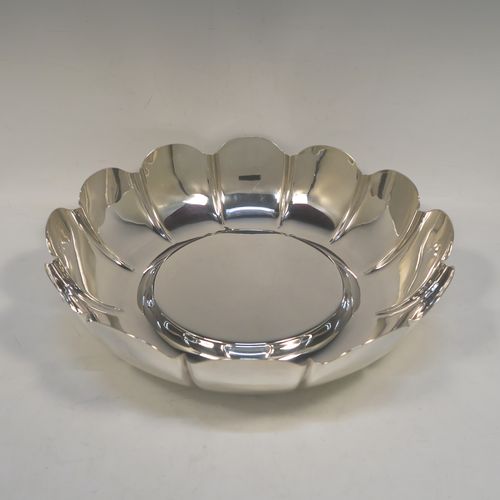 A very large, heavy, and handsome Sterling Silver strawberry dish, having a plain round body, with a raised flat ground, melon fluted sides with hand-chased lobed edges. This elegant silver dish was made by the Royal Irish Silver Co., of London in 1973. The dimensions of this fine hand-made table dish are diameter 33 cms (13 inches), height 8.5 cms (3.3 inches), and it weighs approx. 1,302g (42 troy ounces).   