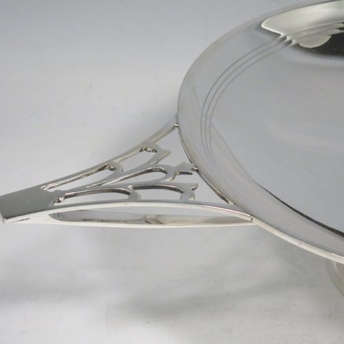 A Sterling Silver Art Deco very stylish serving dish, having a plain round body, with a band of hand-engraved reed-work, and two hand-pierced handles, all sitting on a pedestal foot. Made by William Naylor of Birmingham in 1935. The dimensions of this fine hand-made silver Art Deco dish are width across handles 36.5 cms (14.3 inches), height 7.5 cms (3 inches), and it weighs approx. 520g (16.8 troy ounces).   