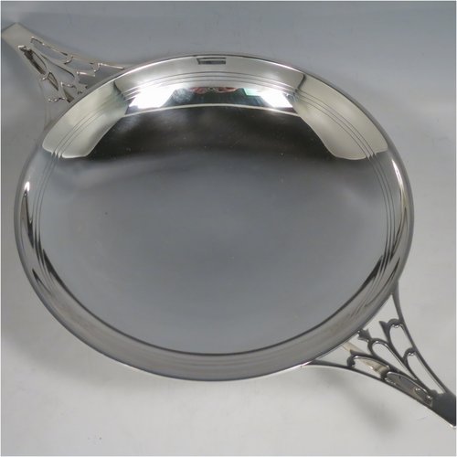 A Sterling Silver Art Deco very stylish serving dish, having a plain round body, with a band of hand-engraved reed-work, and two hand-pierced handles, all sitting on a pedestal foot. Made by William Naylor of Birmingham in 1935. The dimensions of this fine hand-made silver Art Deco dish are width across handles 36.5 cms (14.3 inches), height 7.5 cms (3 inches), and it weighs approx. 520g (16.8 troy ounces).   