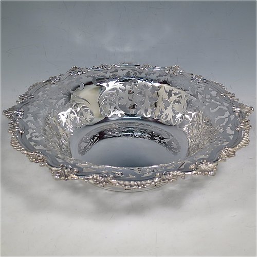 An Antique Edwardian Sterling Silver serving dish, having a round body, with an applied cast scroll and shell border, a hand-pierced body with floral decoration, and sitting on a plain flat collet foot. Made by Alexander Clark of Sheffield in 1906. The dimensions of this fine hand-made antique silver serving dish are 27 cms (10.5 inches) diameter, height 6 cms (2.3 inches), and it weighs approx. 460g (14.8 troy ounces).    