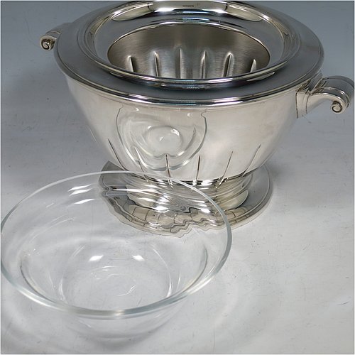 A Sterling Silver Caviar serving dish in an Art Deco style, having a round body with hand-chased straight half-fluting, with two cast scroll side-handles, a removable glass bowl that sits on a rim below which crushed ice can be added, and sitting on a matching pedestal foot. Made by Aspreys & Garrards of London in 2000. The dimensions of this fine hand-made silver caviar serving dish are 17 cms (6..75 inches) diameter, height 11.5 cms (4.5 inches), and it weighs approx. 840g (27 troy ounces).    