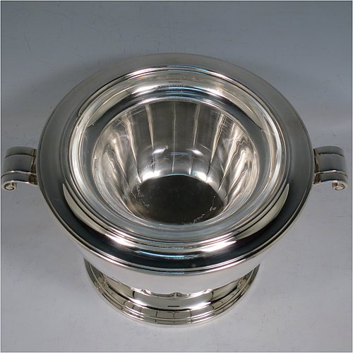 A Sterling Silver Caviar serving dish in an Art Deco style, having a round body with hand-chased straight half-fluting, with two cast scroll side-handles, a removable glass bowl that sits on a rim below which crushed ice can be added, and sitting on a matching pedestal foot. Made by Aspreys & Garrards of London in 2000. The dimensions of this fine hand-made silver caviar serving dish are 17 cms (6..75 inches) diameter, height 11.5 cms (4.5 inches), and it weighs approx. 840g (27 troy ounces).    