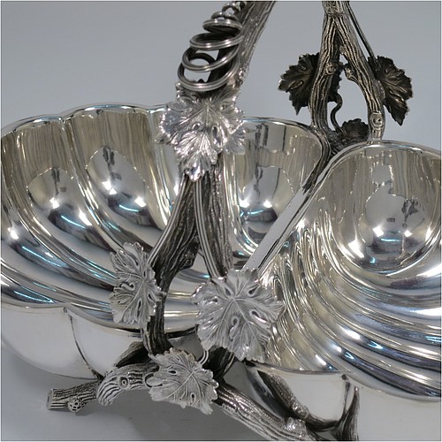 An Antique Victorian Silver Plated very unusual double shell bread roll or biscuit dish, having two connected side dishes with hand-chased shell style decoration, with a central cast vine-leaf and tendril handle, and sitting on four cast branch-like feet. Made by Mappin and Webb in their Princes Plate in ca. 1880. The dimensions of this fine hand-made antique silver-plated biscuit or bread roll dish are length 30 cms (11.75 inches), width 20 cms (8 inches), and height 17 cms (6.75 inches).    