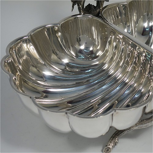 An Antique Victorian Silver Plated very unusual double shell bread roll or biscuit dish, having two connected side dishes with hand-chased shell style decoration, with a central cast vine-leaf and tendril handle, and sitting on four cast branch-like feet. Made by Mappin and Webb in their Princes Plate in ca. 1880. The dimensions of this fine hand-made antique silver-plated biscuit or bread roll dish are length 30 cms (11.75 inches), width 20 cms (8 inches), and height 17 cms (6.75 inches).    