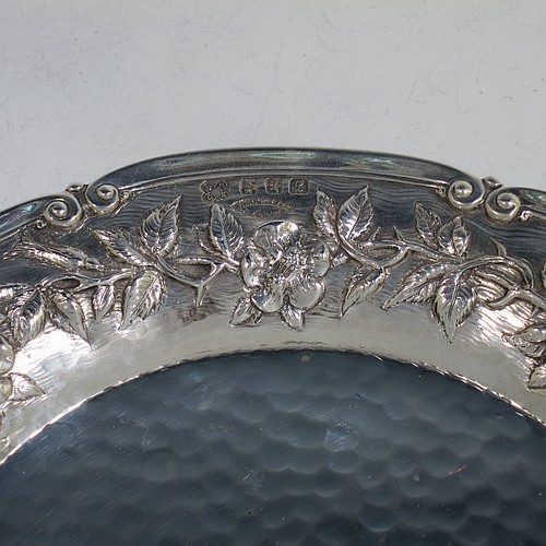 A very pretty Scottish Sterling Silver Arts and Crafts style table dish, having a round hand-hammered body, with an applied scroll border and hand-chased floral wild rose and thorn-leaf decoration. Made by Edward and Sons of Glasgow in 1922. The dimensions of this fine hand-made Arts and Crafts silver dish are diameter 18 cms (7 inches), and it weighs approx. 203g (6.5 troy ounces).    