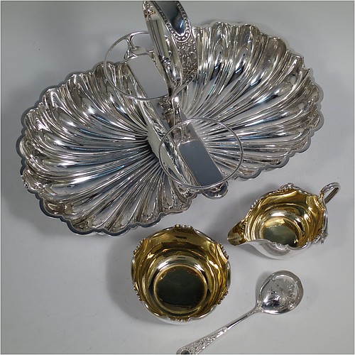 An Antique Victorian Silver-Plated strawberry dish, having two melon-fluted fixed shell dishes, a removable sugar bowl and cream jug both with gold-gilt interiors, an original sugar sifting ladle, and all sitting in a frame with loop handle and four ball feet. Made by James Dixon and Sons of Sheffield in ca. 1880. The dimensions of this fine hand-made antique silver-plated double strawberry dish are length 32 cms (12.5 inches), width 20 cms (8 inches), and height 22 cms (8.75 inches).   