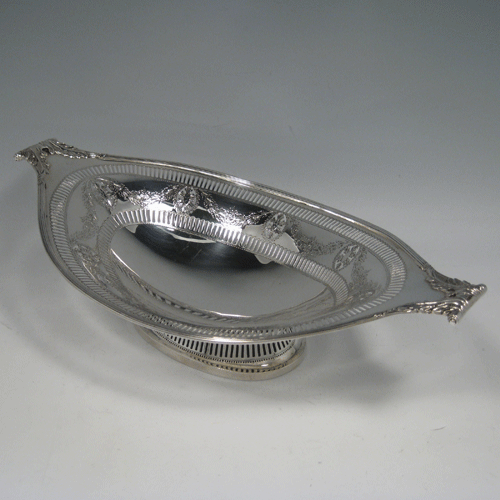 A pretty Antique Edwardian Sterling Silver oval pierced dish with neoclassical style decoration. This beautiful antique silver bread roll dish was made by Thomas Bradbury & Sons of Sheffield in 1910. The dimensions of this fine hand-made silver oval dish are length 32 cms (12.5 inches), width 17.5 cms (7 inches), height 9 cms (3.5 inches), and it weighs approx. 403g (13 troy ounces).