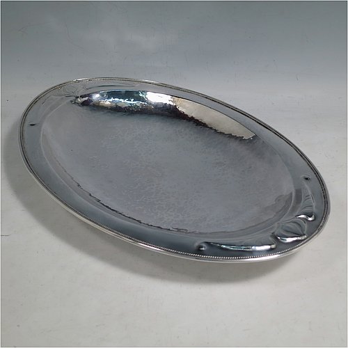 A Sterling Silver Arts and Crafts style dish, having an oval body with hand-hammered decoration, an applied rope-twist border, with hand-chased floral and scroll work at either ends, and all sitting on a collet foot. Made by Henry Charles Hall (from the Swansea School of Crafts) of Sheffield in 1932. The dimensions of this fine hand-made silver table dish are length 31 cms (12.25 inches), width 21 cms (8.25 inches), height 4 cms (1.5 inches), and it weighs approx. 464g (15 troy ounces).    