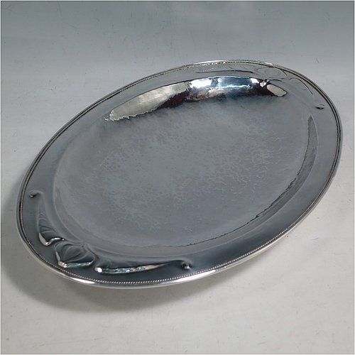 A Sterling Silver Arts and Crafts style dish, having an oval body with hand-hammered decoration, an applied rope-twist border, with hand-chased floral and scroll work at either ends, and all sitting on a collet foot. Made by Henry Charles Hall (from the Swansea School of Crafts) of Sheffield in 1932. The dimensions of this fine hand-made silver table dish are length 31 cms (12.25 inches), width 21 cms (8.25 inches), height 4 cms (1.5 inches), and it weighs approx. 464g (15 troy ounces).    