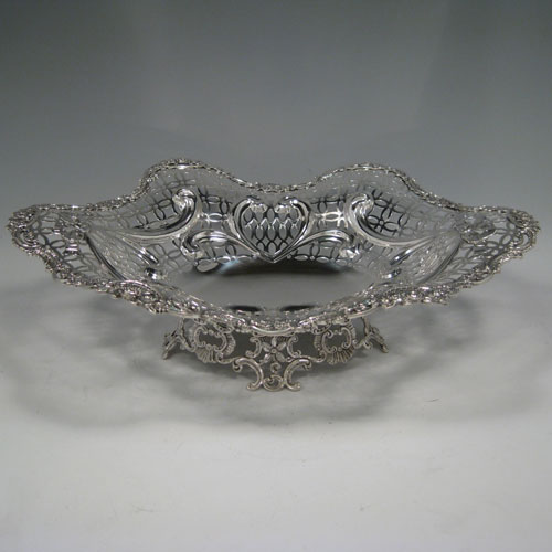 Antique Victorian sterling silver dish, having hand-pierced decoration with swags and bows, with a cast foliate border, and sitting on a matching cast foliate foot. Made by William Comyns of London in 1894. The dimensions of this fine hand-made silver table dish are length 36 cms (14.25 inches), width 28 cms (11 inches), height 10 cms (4 inches), and it weighs approx. 25 troy ounces (775g).