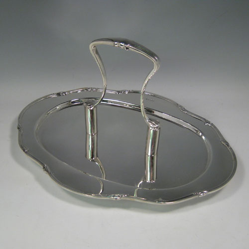 A heavy and very stylish Art Deco Sterling Silver unusual flat serving dish with carrier handle, with an applied reeded and floral border, all sitting on four cast flange feet. This unique silver serving dish was made by Charles Boyton & Sons of Sheffield in 1931. The dimensions of this fine hand-made serving dish are height 19 cms (7.5 inches), length 34.5 cms (13.5 inches), width 26 cms (10.25 inches), and it weighs approx. 1,156g (37.2 troy ounces).