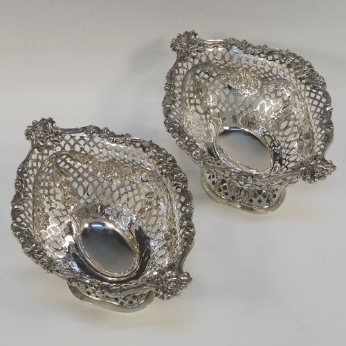 A very pretty pair of Antique Victorian Sterling Silver dishes, having oval bodies with neoclassical style decoration, hand-pierced with swags and bows and applied cast foliate borders, all sitting on matching oval pedestal feet. These beautiful antique silver dishes were made by Charles Stuart Harris of London in 1900. The dimensions of these fine hand-made silver table dishes are length 19 cms (7.5 inches), width 14 cms (5.5 inches), height 11 cms (4.3 inches), and they weigh a total of approx. 627g (20 troy ounces).   