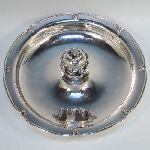 A very elegant and unusual Sterling Silver Arts and Crafts style large table fruit dish, having a round hand-hammered body, a central handle with cast grape and fruit decoration, and an applied grape border. Made by A. E. Jones of Birmingham in 1936. The dimensions of this fine hand-made silver fruit dish are diameter 31 cms (12.25 inches), height 10 cms (4 inches), and it weighs approx. 1,080g (34.8 troy ounces).  