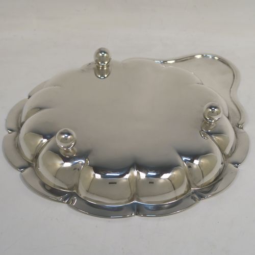 An elegant Antique Edwardian Sterling Silver strawberry dish, having a plain round body with a hand-chased lobed border, a plain side handle, and all sitting on three ball feet. This handsome antique silver strawberry dish was made by the Atkins Brothers of Sheffield in 1905. The dimensions of this fine hand-made antique silver dish are length 25 cms (9.75 inches), diameter of main body 20 cms (8 inches), and it weighs approx. 293g (9 troy ounces).  