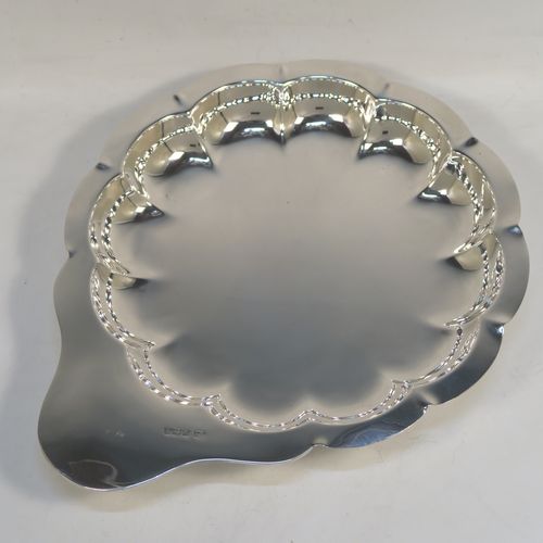 An elegant Antique Edwardian Sterling Silver strawberry dish, having a plain round body with a hand-chased lobed border, a plain side handle, and all sitting on three ball feet. This handsome antique silver strawberry dish was made by the Atkins Brothers of Sheffield in 1905. The dimensions of this fine hand-made antique silver dish are length 25 cms (9.75 inches), diameter of main body 20 cms (8 inches), and it weighs approx. 293g (9 troy ounces).  