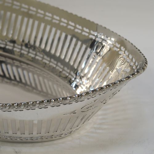 A very pretty Antique Sterling Silver bread roll table dish, having an oval body with hand-pierced geometrical and floral style decoration, an applied gadroon top border, and sitting on a flat base. This beautiful antique silver bread roll dish was made by the Barker Brothers of Chester in 1911. The dimensions of this fine hand-made silver bread dish are length 30 cms (11.75 inches), width 17.5 cms (7 inches), height 7.5 cms (3 inches), and it weighs approx. 389g (12.5 troy ounces).   