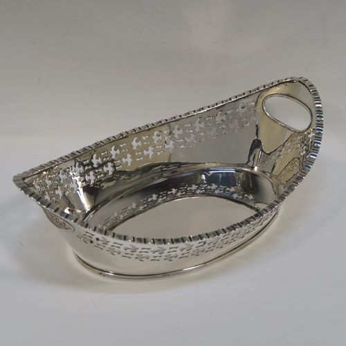 A very elegant Antique Victorian sterling silver bread roll table dish, having an oval body with hand-pierced floral style decoration, an applied gadroon top border, with two cut-out oval side handles, and sitting on a flat base. This handsome antique silver bread roll dish was made by Gibson and Langland of London in 1899. The dimensions of this fine hand-made silver bread dish are length 27.5 cms (10.75 inches), width 17 cms (6.75 inches), height 9 cms (3.5 inches), and it weighs approx. 538g (17.4 troy ounces).   