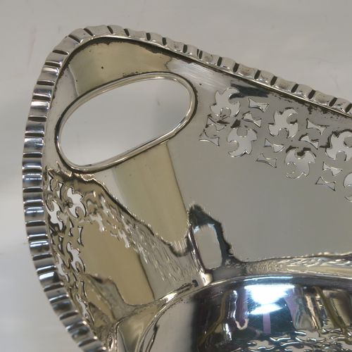 A very elegant Antique Victorian sterling silver bread roll table dish, having an oval body with hand-pierced floral style decoration, an applied gadroon top border, with two cut-out oval side handles, and sitting on a flat base. This handsome antique silver bread roll dish was made by Gibson and Langland of London in 1899. The dimensions of this fine hand-made silver bread dish are length 27.5 cms (10.75 inches), width 17 cms (6.75 inches), height 9 cms (3.5 inches), and it weighs approx. 538g (17.4 troy ounces).   