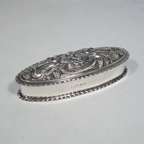 A very pretty Antique Edwardian Art Nouveau Sterling Silver dressing table box, having an oval body with crimped borders, a hinged lid with hand-chased floral, scroll, and Cherub work, and sitting on a flat base. Made by Levi & Salamon of Birmingham in 1902. The dimensions of this fine hand-made silver dressing table box are length 11 cms (4.25 inches), width 4 cms (1.5 inches), height 3 cms (1.25 inches), and it weighs approx. 165g (2 troy ounces).   