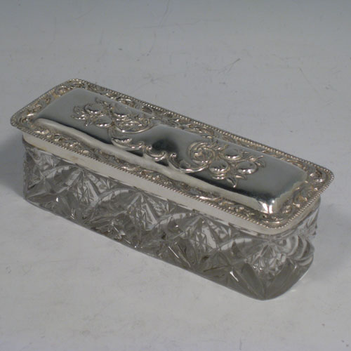    Antique Edwardian sterling silver and crystal dressing table jar / box, having a pull-off lid with hand-chased floral decoration, and a rectangular hand-cut crystal body. Made in Birmingham in 1906. Length 12 cms (4.75 inches), width 4.5 cms (1.75 inches), height 4 cms (1.5 inches).