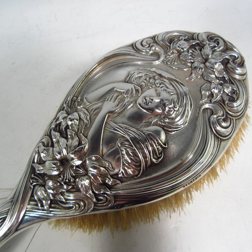 An Antique Edwardian Sterling silver Art Nouveau dressing table hair brush, having very pretty hand-chased floral and ribbon decoration, surrounding a figure of a lady. All with original bristles and wooden mount in very good condition. Made by Henry Miller of Birmingham in 1903. The dimensions of this fine hand-made hair brush are length 24 cms (9.5 inches), and width 9 cms (3.5 inches).