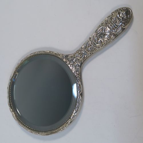 A very pretty Sterling Silver four-piece dressing table, consisting of a hand-mirror with a bevelled mirror, a hair brush, a clothes brush, and a hand comb, all hand-chased with floral and scroll decoration, with nylon bristles, and in their original cream satin-lined and blue presentation box. This beautiful silver dressing table set was made in Birmingham in 2002. The dimensions of this fine hand-made sterling silver dressing table service are length of hand mirror 24 cms (9.5 inches), length of hair brush 23 cms (9 inches), and length of clothes brush 15 cms (6 inches).   