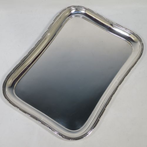 A pretty Antique Edwardian Sterling Silver dressing table tray, having a rectangular body with rounded corners, a plain ground, an applied laurel-leaf and reeded border, and all sitting on a flat base. Made by Harrison Brothers and Howson of Sheffield in 1910. The dimensions of this fine hand-made ique antsilver dressing table tray are length 30 cms (12 inches), width 22 cms (8.75 inches), and it weighs approx. 512g (16.5 troy ounces).    