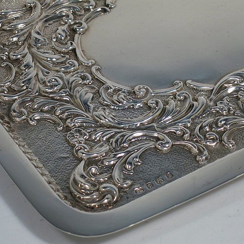 An Antique Edwardian Sterling Silver dressing table pin tray, having a rectangular body with a raised fluted border, hand-chased floral and scroll decoration on a hand-hammered ground, with a central vacant cartouche, and all sitting on a flat base. Made by William Aitken of Birmingham in 1909. The dimensions of this fine hand-made antique silver pin or dressing table tray are length 27 cms (10.5 inches), width 19 cms (7.5 inches), and it weighs approx. 216g (7 troy ounces).       