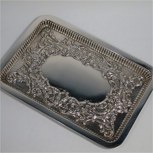 An Antique Edwardian Sterling Silver dressing table pin tray, having a rectangular body with a raised fluted border, hand-chased floral and scroll decoration on a hand-hammered ground, with a central vacant cartouche, and all sitting on a flat base. Made by William Aitken of Birmingham in 1909. The dimensions of this fine hand-made antique silver pin or dressing table tray are length 27 cms (10.5 inches), width 19 cms (7.5 inches), and it weighs approx. 216g (7 troy ounces).       