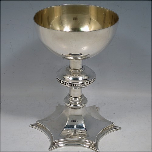 A Sterling Silver altar chalice and paten, having a plain round tapering cup with gold-gilt interior, a round column with a middle baluster and bead border, and a spreading hexagonal pedestal foot, together with a plain round paten with hand-engraved cross. The chalice made by Frederick Osborne of London in 1931, and the paten by Jones and Willis of London in 1908. The dimensions of this fine hand-made silver chalice & paten are height 15 cms (6 inches), diameter of cup 10 cms (4 inches), diameter of paten 13.5 cms (5.3 inches), and it weighs a total of 455g (14.7 troy ounces). 