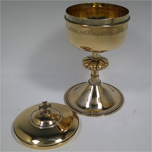 A very beautiful Sterling Silver and Gold-Gilt Ciborium, having a round body with a band of hand-engraved floral motifs, a plain round lift-off lid with cast cruciform finial, a hand-chased swirl-fluted central baluster, and all sitting on a round pedestal foot base with hand-engraved oval cartouches of wheat-sheaves and applied rope-twist borders. Made by Hayes and Finch Ltd., of London in 1951. The dimensions of this fine hand-made silver and gold-gilt ciborium are height 23.5 cms (9.25 inches), diameter of cup 12 cms (4.75 inches), and it weighs a total of approx. 730g (23.5 troy ounces).    