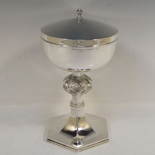 A very handsome and heavy Sterling Silver Ciborium, having a plain round body with a gold-gilt interior, a plain round lift-off lid with a cast urn-shaped finial, a hand-chased floral and jewel style central baluster, and all sitting on a hexagonal pedestal foot with applied reeded borders. This elegant silver ciborium was made by A. L. Davenport of Birmingham in 1938. The dimensions of this fine hand-made silver ciborium are height 23 cms (9 inches), diameter of cup 12.5 cms (5 inches), and it weighs a total of approx. 795g (25.6 troy ounces).