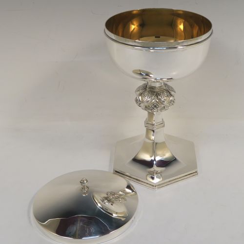 A very handsome and heavy Sterling Silver Ciborium, having a plain round body with a gold-gilt interior, a plain round lift-off lid with a cast urn-shaped finial, a hand-chased floral and jewel style central baluster, and all sitting on a hexagonal pedestal foot with applied reeded borders. This elegant silver ciborium was made by A. L. Davenport of Birmingham in 1938. The dimensions of this fine hand-made silver ciborium are height 23 cms (9 inches), diameter of cup 12.5 cms (5 inches), and it weighs a total of approx. 795g (25.6 troy ounces).