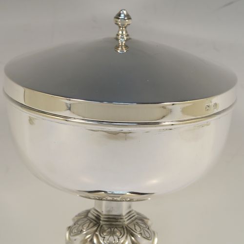 A very handsome and heavy Sterling Silver Ciborium, having a plain round body with a gold-gilt interior, a plain round lift-off lid with a cast urn-shaped finial, a hand-chased floral and jewel style central baluster, and all sitting on a hexagonal pedestal foot with applied reeded borders. This elegant silver ciborium was made by A. L. Davenport of Birmingham in 1938. The dimensions of this fine hand-made silver ciborium are height 23 cms (9 inches), diameter of cup 12.5 cms (5 inches), and it weighs a total of approx. 795g (25.6 troy ounces).