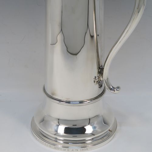 A handsome and large Antique Victorian Sterling Silver ecclesiastical wine flagon ewer, having a round straight-sided body with tapering sides and  applied reeded bands, a side scroll handle, together with a hinged domed lid and cast fluted finial, a sparrow-beak spout, and sitting on a spreading collet foot. This elegant silver church consecrated wine flagon was made by the Barnard Brothers of London in 1850. The dimensions of this fine hand-made antique silver flagon or ewer are height 34.5 cms (13.5 inches), diameter at base 14.5 cms (5.75 inches), and it weighs approx. 980g (31.6 troy ounces).   