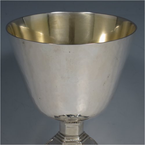 A Sterling Silver Chalice having a round body with a hand-hammered finish, a hexagonal pedestal foot with a central baluster, having applied bead borders, a gold-gilt interior, and a hand-chased crucifix. Made by Frederick Osbourne of London in 1933. The dimensions of this fine hand-made chalice are height 20 cms (8 inches), diameter at lip 10 cms (4 inches), and it weighs approx. 682g (22 troy ounces).   