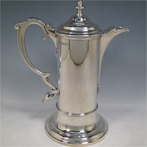 An Antique Victorian Sterling Silver communion flagon for wine, in an early 17th century style having a straight-sided body, a scroll handle, a hinged & domed lid with urn-shaped finial, a matching scrolled spout and sitting on a collet foot. Made by Robert Garrard of London in 1863. The dimensions of this fine hand-made communion flagon are height 29 cms (11.5 inches), length across handle & spout 23 cms (9 inches),and it weighs approx. 1,092g (35 troy ounces).   